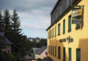 ein gelbes Gebäude mit einem Schild an der Seite in der Unterkunft Landgasthof Zur Fichte in Bärenstein