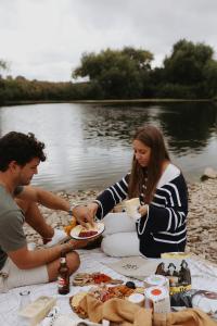 a man and woman sitting at a picnic table with food at White House on Wye Glamping in Hereford
