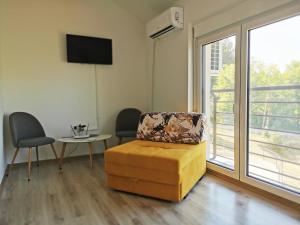 uma sala de estar com um repousa-pés amarelo e uma janela em Vila Una Fruška gora em Novi Sad