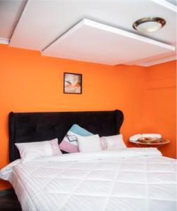 ein Schlafzimmer mit einem Bett mit einer orangefarbenen Wand in der Unterkunft Kasbek Lodge & Tours in Kazungula