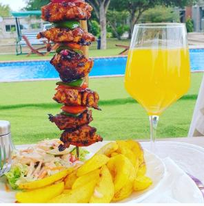 a plate of food with a sandwich and chips and a glass of juice at Kasbek Lodge & Tours in Kazungula