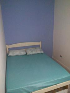 Cama pequeña en habitación con pared azul en Residencial Solar de Pernambuco, en Guarujá