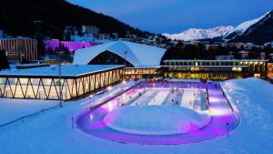 ein Gebäude mit Eislaufbahn im Schnee in der Nacht in der Unterkunft Hotel Steinbock in Klosters