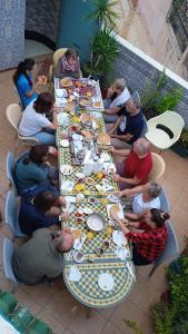 eine Gruppe von Menschen, die an einem langen Tisch mit Essen sitzen in der Unterkunft Riad Malak in Meknès