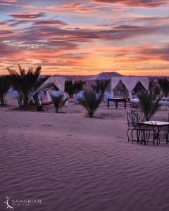 a sunset in the desert with tents in the sand at Saharian Luxury Camp Deluxe Familly Quadriple in Merzouga