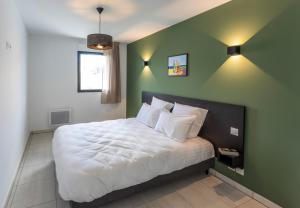 - une chambre avec un grand lit aux murs verts dans l'établissement Nemea Appart Hotel Les Hauts de Milady Biarritz, à Biarritz