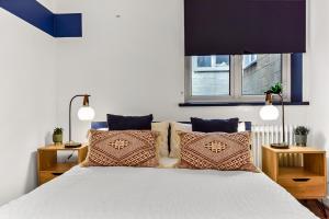 1 dormitorio con cama con almohadas y ventana en Spacious Cosy 2 Bed Flat, Central London, en Londres