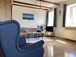 - un salon avec un fauteuil bleu et un canapé dans l'établissement Ferienhof Weber Nieratz, à Wangen im Allgäu
