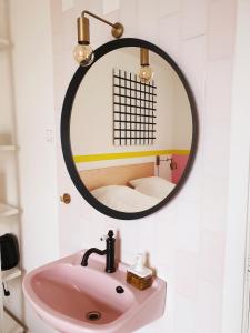 W łazience znajduje się różowa umywalka i lustro. w obiekcie Sonnevanck Wijk aan Zee w mieście Wijk aan Zee
