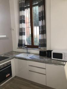 una cucina bianca con lavandino e finestra di Appartamento Colomba a Piacenza