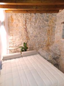 uma cama num quarto com uma parede de pedra em WUNDERGARTEN Rural Spa House em Gratteri