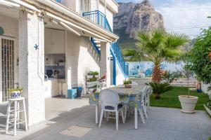 a patio with a table and chairs with a mountain in the background at Villa Vista Mare Cinisi in Cinisi