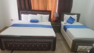 1 dormitorio con 2 camas con sábanas azules y blancas en Hotel Day IN One, en Lahore