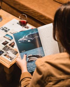 a woman reading a book on a table with a glass of wine at Chepatagonia Hostel & Coworking in Puerto Madryn