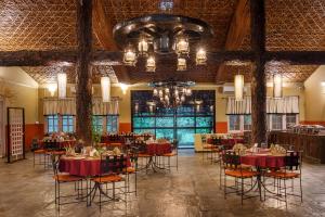 uma sala de jantar com mesas e cadeiras e um lustre em Green Mansions Jungle Resort em Sauraha