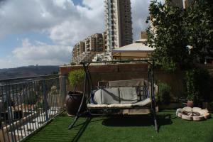 a chair sitting on the grass on a balcony at Holyland Apartments in Jerusalem