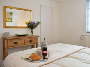 a plate of bread and croissants on a bed at Manor Cottage in Findon