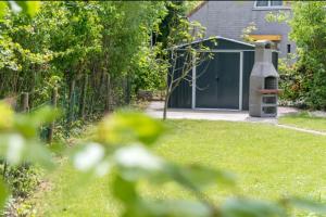 un jardín con un cobertizo verde con parrilla en Kustverhuur, Vakantiepark Fort Soleil 28 en Breskens