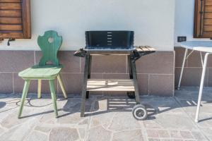 una parrilla y dos sillas sentadas junto a una pared en Appartamento Tra i Due Laghi, en Baselga di Pinè