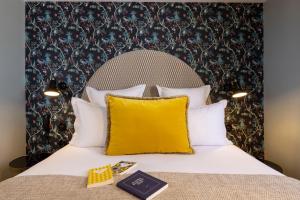 a bed with a yellow pillow and a book at Hotel Fior d'Aliza in Paris
