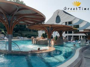 a pool at a resort with people in the water at Great Time Apartman in Hévíz