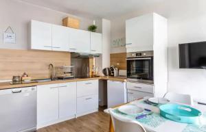 a kitchen with white cabinets and a table with chairs at T1Bis centre d'Arcachon avec balcon in Arcachon