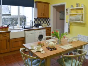 a kitchen with a wooden table with chairs and a sink at Fairground Cottage in Rothbury