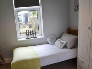 a small bedroom with a bed with a window at Fairground Cottage in Rothbury