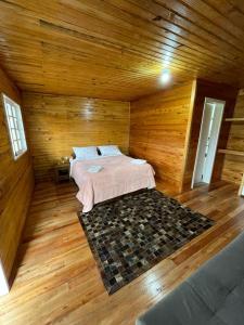 ein Schlafzimmer mit einem Bett in einem Holzzimmer in der Unterkunft Paraíso do Campestre in Urubici