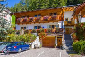 a house with a blue car parked in front of it at Appartamenti Sonnenuhr in Sesto