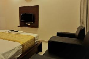 a hotel room with a bed and a chair at Gateway Inn in Bangalore