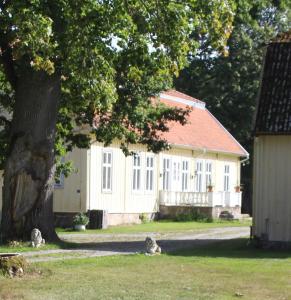 Una casa blanca con un árbol delante. en Yxkullsund Säteri B&B - Manor & Estate since 1662, en Lagan