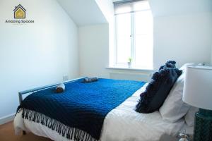 a bedroom with a bed with a blue blanket and a window at Cosy 2 Bed Flat Sleeps 4 with Free Parking by Amazing Spaces Relocations Ltd in Warrington