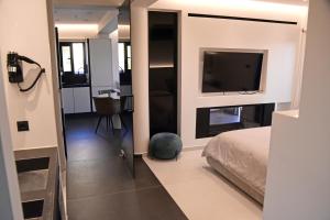 a bedroom with a bed and a flat screen tv at White and Black Aegina in Áyioi Asómatoi