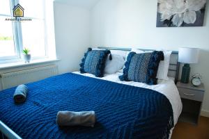 a bedroom with a bed with a blue comforter and pillows at Cosy 2 Bed Flat Sleeps 4 with Free Parking by Amazing Spaces Relocations Ltd in Warrington