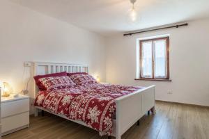 a bedroom with a bed with a red comforter and a window at Appartamento Edik in Folgaria
