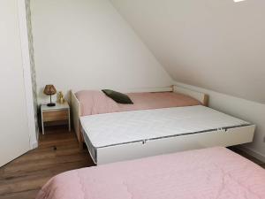 two beds in a small room with pink sheets at Le Séduisant in Sainte-Anne-sur-Vilaine