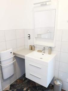 a white bathroom with a sink and a mirror at Le Séduisant in Sainte-Anne-sur-Vilaine