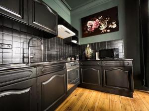 a kitchen with black cabinets and a sink and a microwave at Alice in Spa