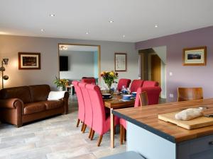 a kitchen and dining room with a table and red chairs at Brewers Cottage in Slaley