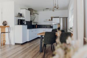 a kitchen with white cabinets and a table and chairs at Allgäu-FeWo-Niso in Waltenhofen +10 photos