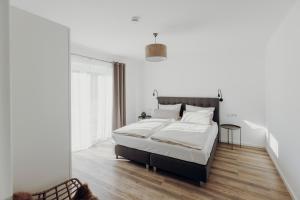 a bedroom with a bed with white walls and wooden floors at Allgäu-FeWo-Niso in Waltenhofen