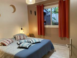 um quarto com uma cama com almofadas e uma janela em Bungalow Tec-Tec St Leu em Saint-Leu