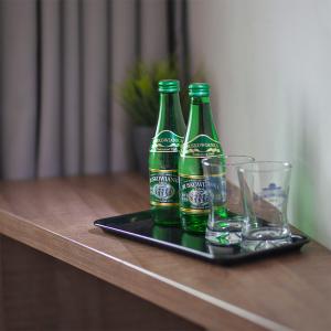 three bottles of beer on a tray with glasses on a table at Abton Hotel in Łódź