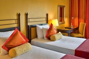 a hotel room with two beds and a chair at Corinthia St George's Bay in St. Julianʼs