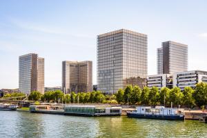 een stad met hoge gebouwen en een rivier met boten bij Residhome Quai d’Ivry in Ivry-sur-Seine