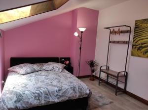 een slaapkamer met een bed en een roze muur bij Chez Sam in Villebois