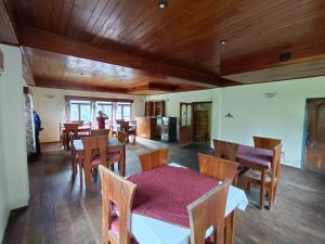 uma sala de jantar com tectos de madeira e mesas e cadeiras de madeira em Hotel Pemathang em Pemayangtse