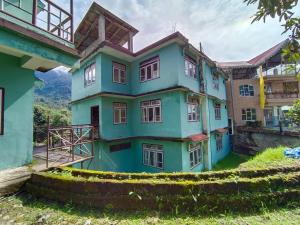 a blue house with a hill in the background at Hotel Pemathang in Pemayangtse