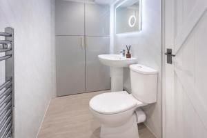 a white bathroom with a toilet and a sink at Eden's Peaceful Escape Apartment in Kendal